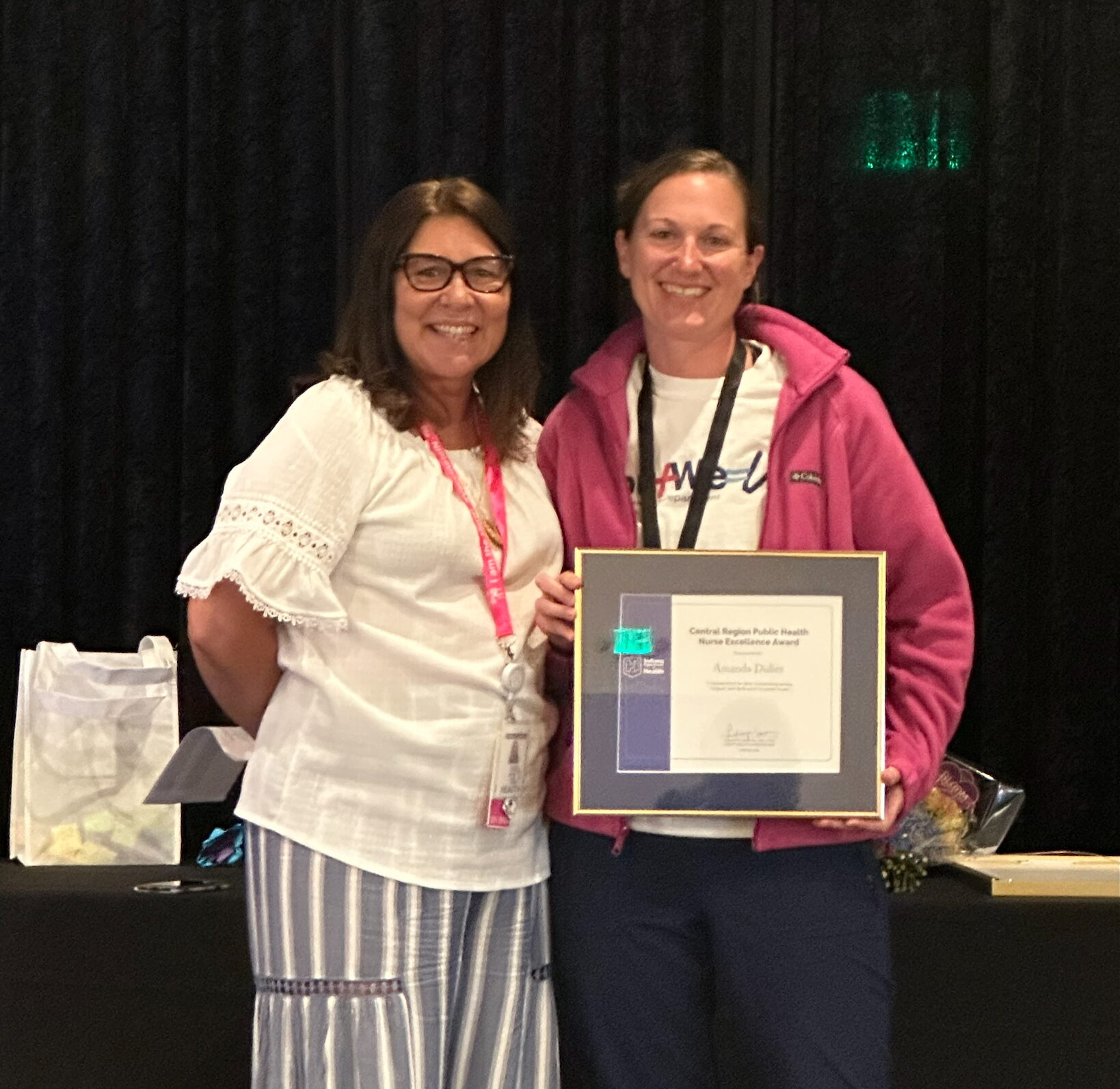 amanda standing next to a woman, smiling holding an award